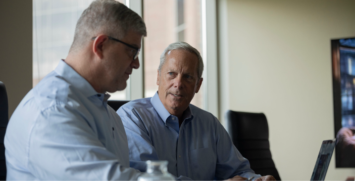 Two senior investment bankers discussing a deal in a conference room