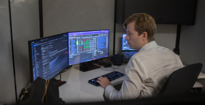 An investment banker looking closely at his computer monitors