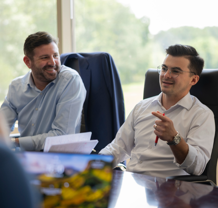 Two investment bankers smiling at a conference table