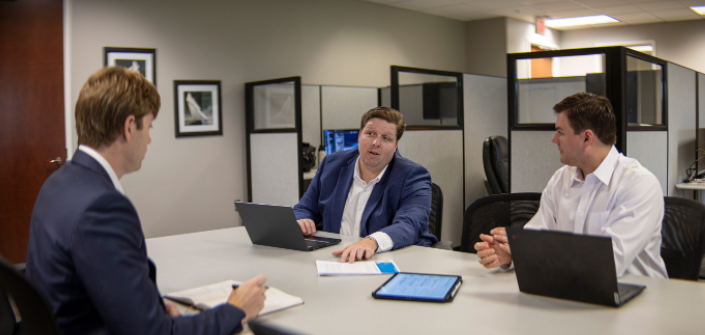 Three bankers discussing a deal around a conference table in their office